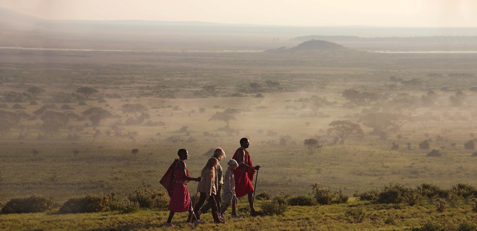 Two local masaai tribe members guide a family on a family vacation in Kenya