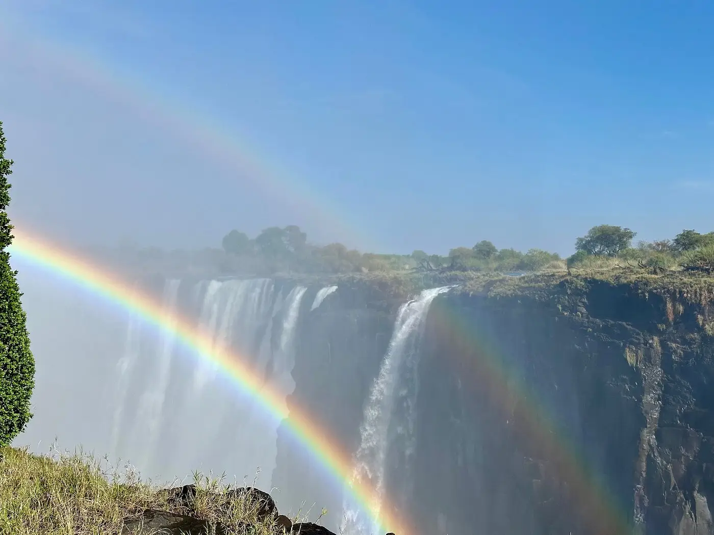 Our American guests from Florida capturing a rainbow arching over Victoria Falls, observing hippos in the Zambezi River, and viewing their outside suite at Victoria Falls River Lodge - Island Treehouse Suites